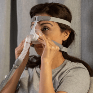 Mujer ajustandose la Mascarilla nasal Wizard 310 para tratamiento de apnea del sueño con diseño ligero y visión despejada.