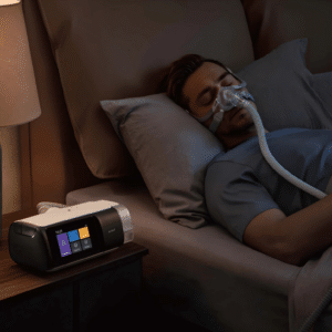 Hombre durmiendo pacíficamente en la cama. El dispositivo de terapia de sueño CPAP Yuwell Breathcare III YH-680 está visible y encendido sobre la mesilla de noche a su lado.